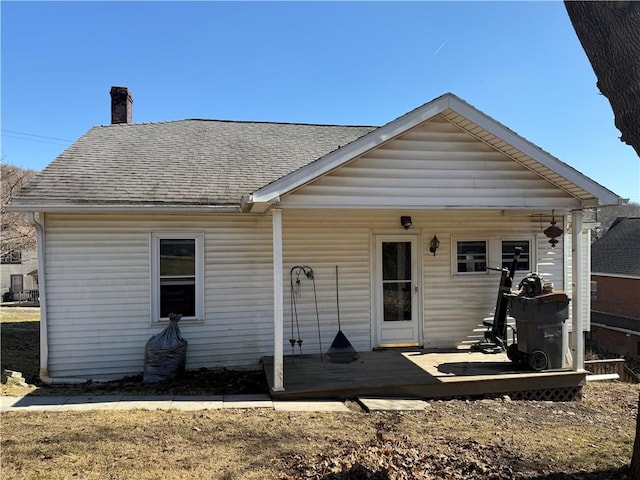 back of property featuring a chimney and a shingled roof