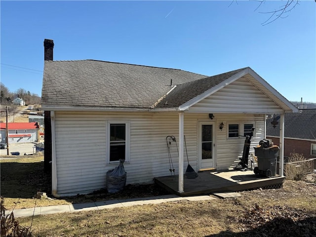 rear view of property with a chimney and a shingled roof