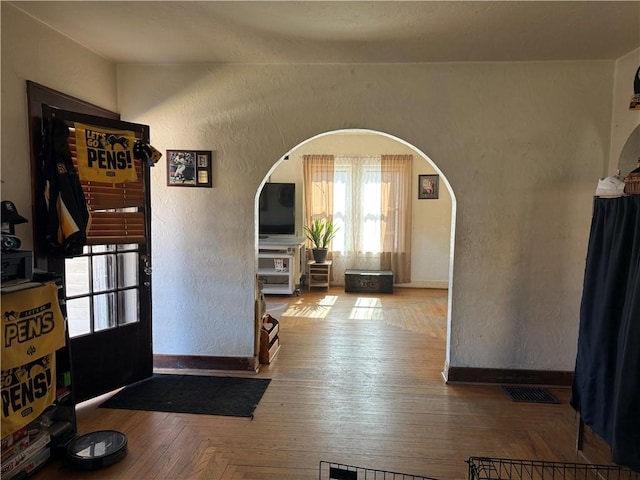 entrance foyer featuring visible vents, arched walkways, and a textured wall