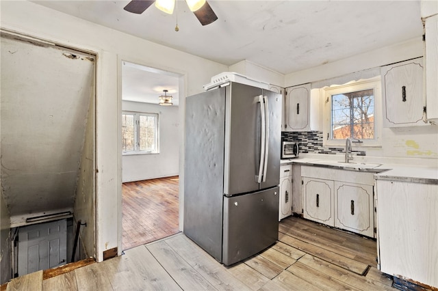 kitchen with light countertops, light wood finished floors, tasteful backsplash, and freestanding refrigerator