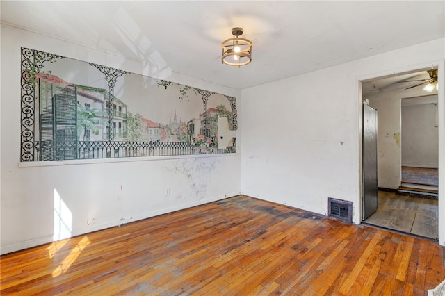 empty room featuring visible vents, hardwood / wood-style floors, and a ceiling fan