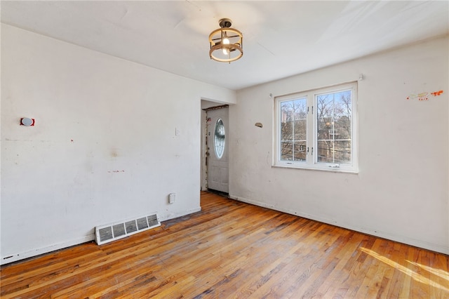 spare room with visible vents, wood-type flooring, and baseboards