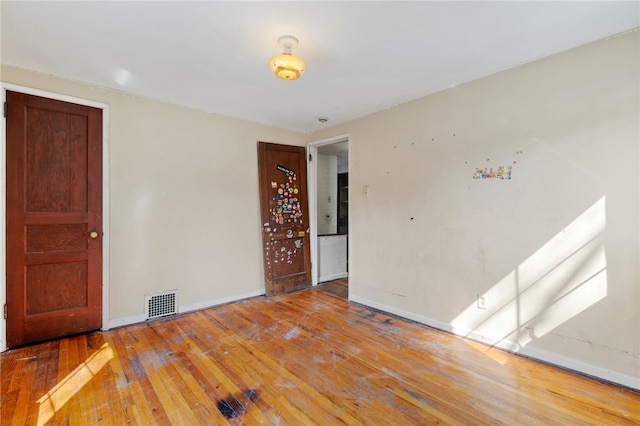 empty room with visible vents, baseboards, and hardwood / wood-style flooring