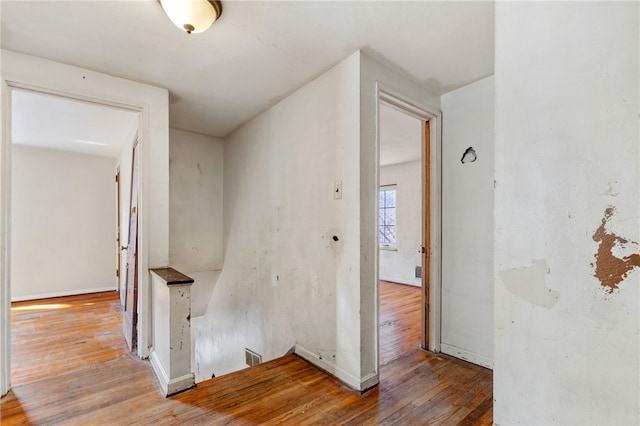 hall featuring an upstairs landing, baseboards, and hardwood / wood-style flooring