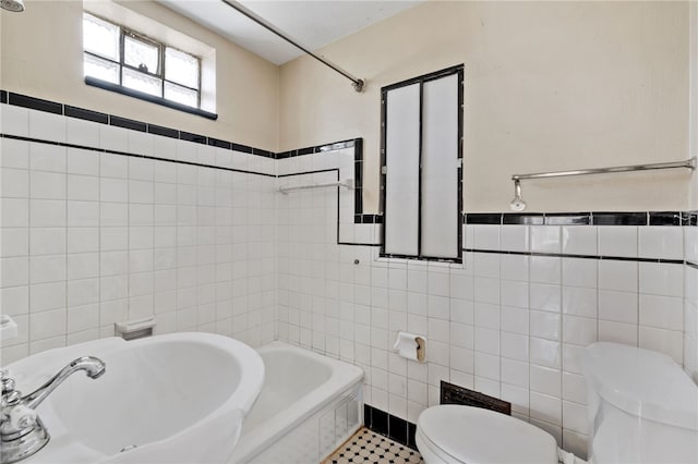 full bathroom with tile walls, toilet, a bathing tub, and a sink