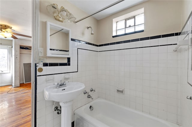 full bath with bathtub / shower combination, tile walls, wood finished floors, and a ceiling fan