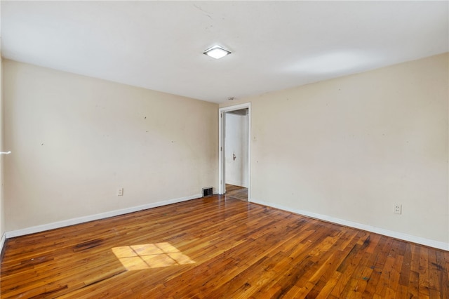 spare room featuring visible vents, baseboards, and hardwood / wood-style floors