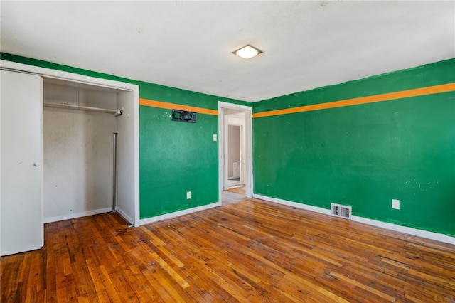 unfurnished bedroom featuring a closet, baseboards, visible vents, and wood-type flooring