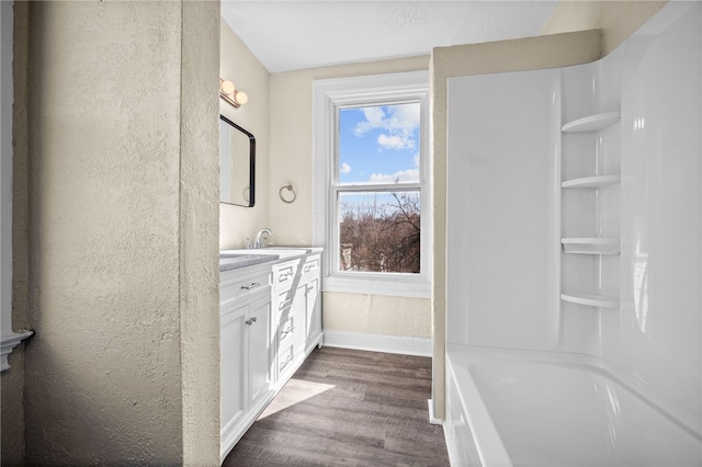 bathroom featuring baseboards, shower / tub combination, wood finished floors, and vanity