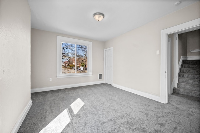 carpeted spare room with visible vents, stairs, and baseboards