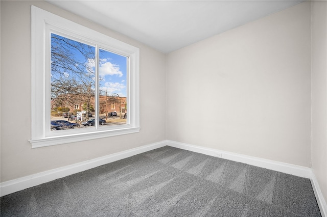 spare room with baseboards and carpet floors