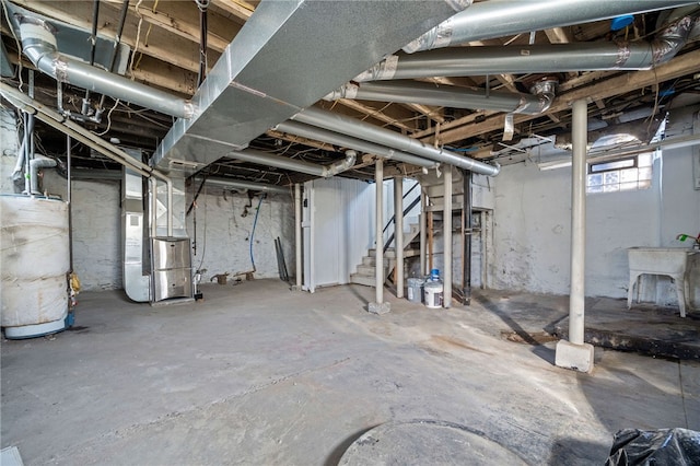 basement featuring gas water heater, stairway, and heating unit