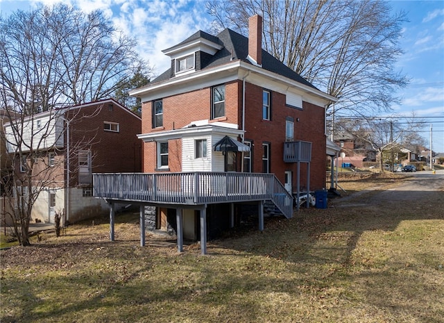 back of house with a wooden deck, a yard, brick siding, and a chimney