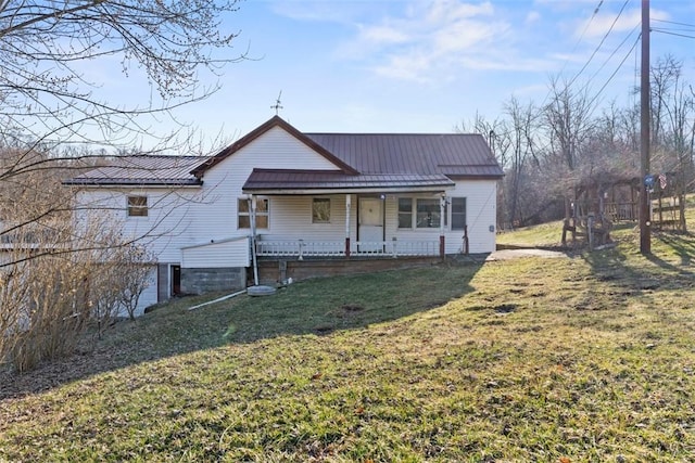 rear view of property with metal roof, a lawn, covered porch, and a standing seam roof