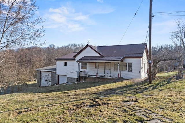 rear view of house featuring covered porch, a lawn, and metal roof