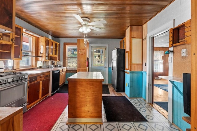 kitchen with a center island, gas range oven, freestanding refrigerator, light countertops, and dishwasher