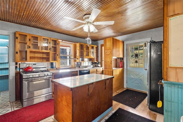 kitchen featuring a kitchen island, glass insert cabinets, appliances with stainless steel finishes, a ceiling fan, and a sink