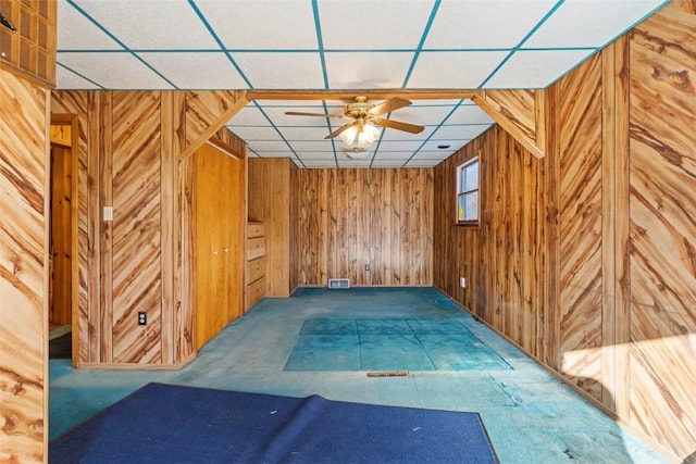 bonus room featuring wooden walls, carpet, visible vents, and ceiling fan