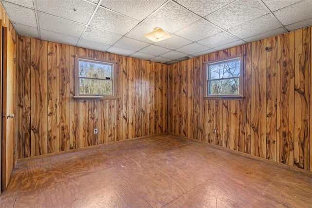 unfurnished room with wood walls and a paneled ceiling