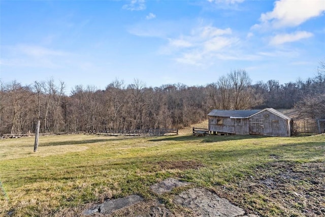 view of yard featuring a forest view, an outbuilding, a barn, and fence