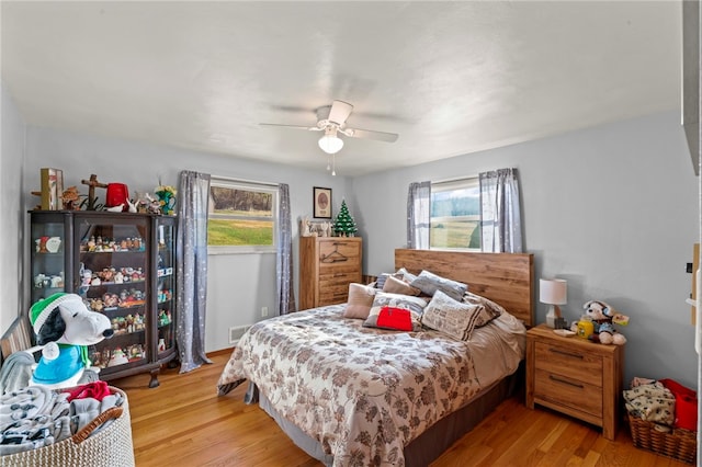 bedroom with multiple windows, light wood-type flooring, and ceiling fan