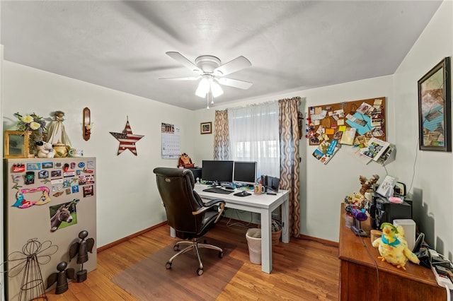 office featuring a ceiling fan, light wood-style floors, and baseboards