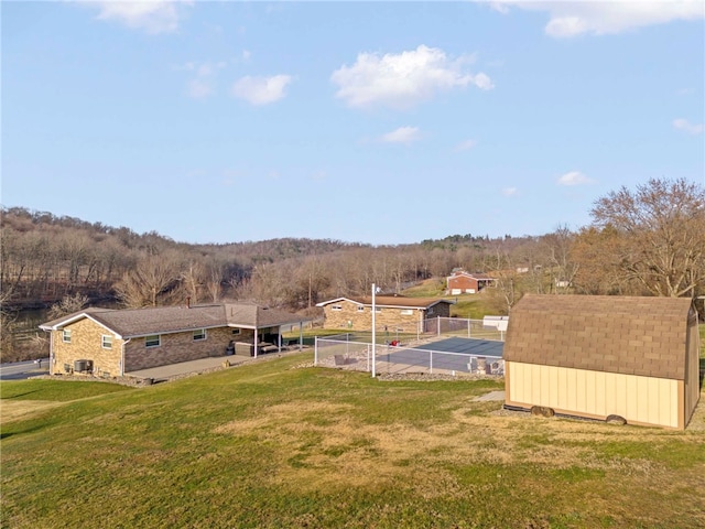 view of yard with central AC unit, an outbuilding, a storage unit, and fence