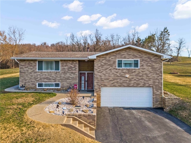 raised ranch with aphalt driveway, a front yard, a garage, and brick siding