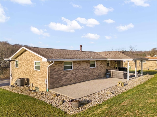 rear view of property with roof with shingles, central AC, a lawn, a patio area, and brick siding