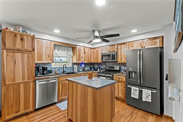 kitchen with backsplash, appliances with stainless steel finishes, light wood-style floors, and a sink