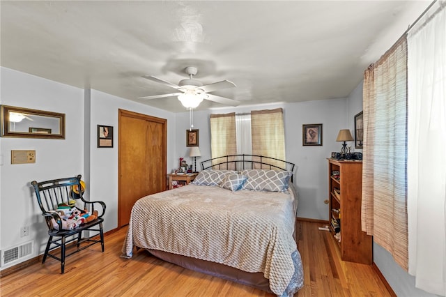 bedroom with visible vents, ceiling fan, baseboards, wood finished floors, and a closet