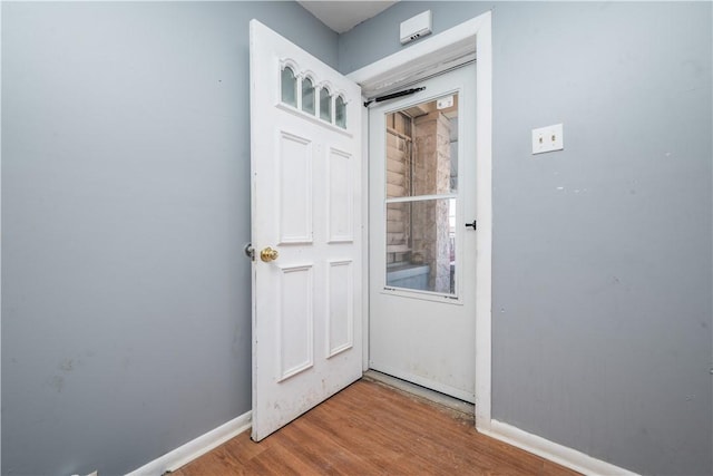 doorway with baseboards and wood finished floors