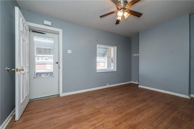 empty room with ceiling fan, baseboards, and wood finished floors