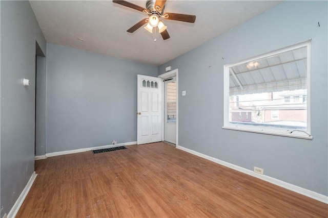 unfurnished room with visible vents, baseboards, wood finished floors, and a ceiling fan