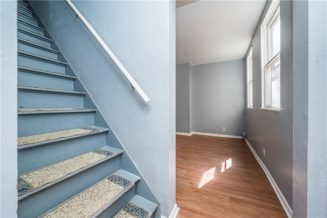 staircase featuring wood finished floors and baseboards