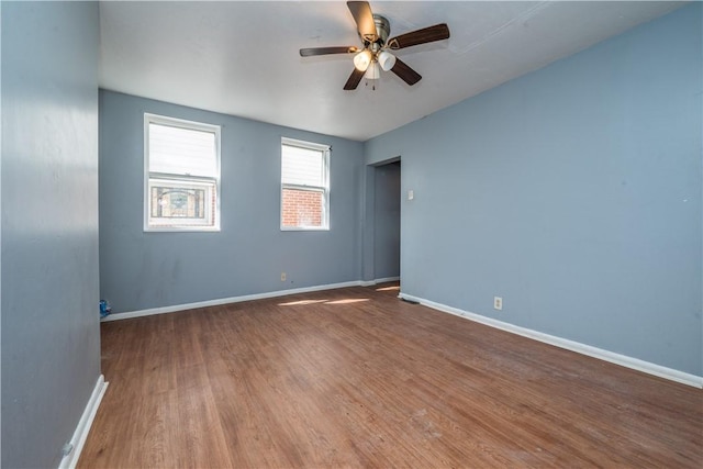 empty room featuring wood finished floors, baseboards, and ceiling fan