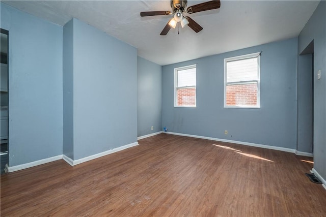 empty room with ceiling fan, baseboards, and wood finished floors