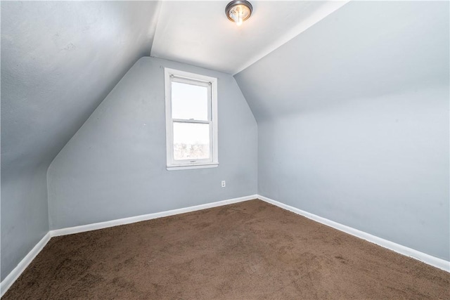 additional living space featuring vaulted ceiling, baseboards, and dark carpet