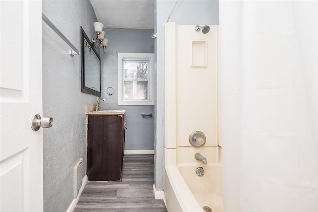 bathroom with shower / bath combination, baseboards, wood finished floors, and vanity