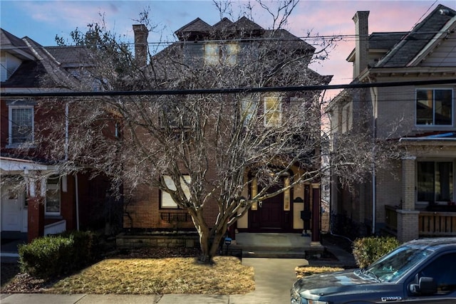 view of front facade with brick siding and a chimney