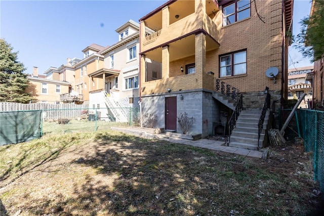 rear view of property with brick siding, a residential view, stairs, and fence