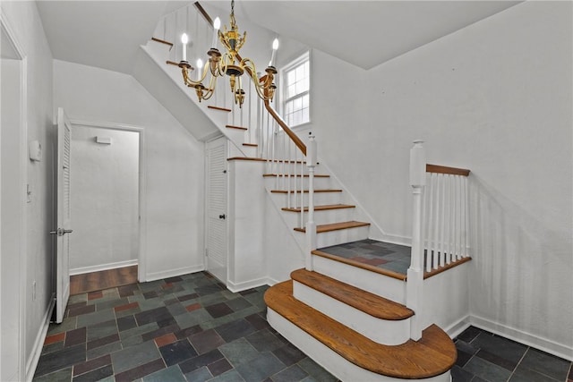 stairs with an inviting chandelier, stone finish floor, and baseboards