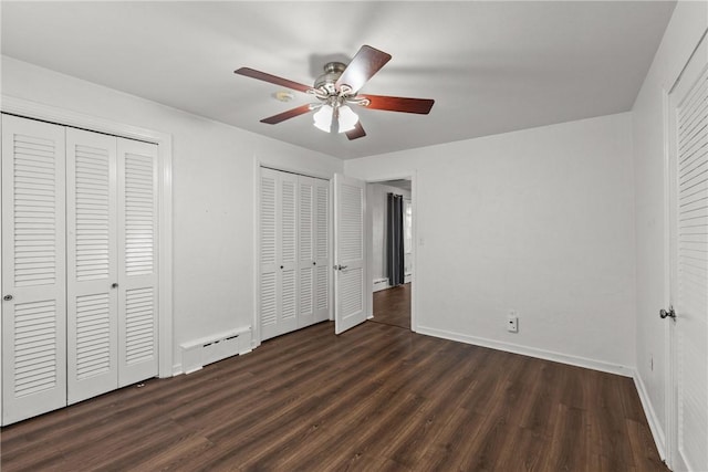 unfurnished bedroom featuring baseboards, multiple closets, baseboard heating, wood finished floors, and a ceiling fan