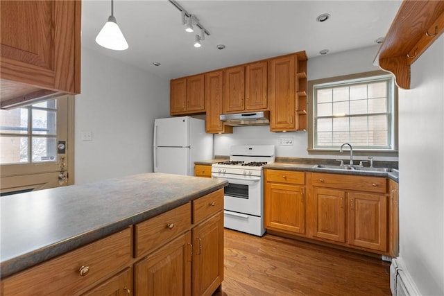 kitchen featuring white appliances, a sink, under cabinet range hood, dark countertops, and baseboard heating