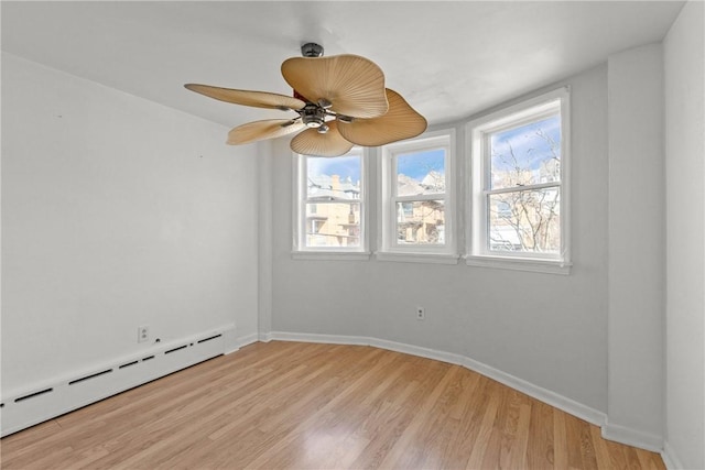 empty room with a ceiling fan, baseboards, light wood-type flooring, and a baseboard radiator