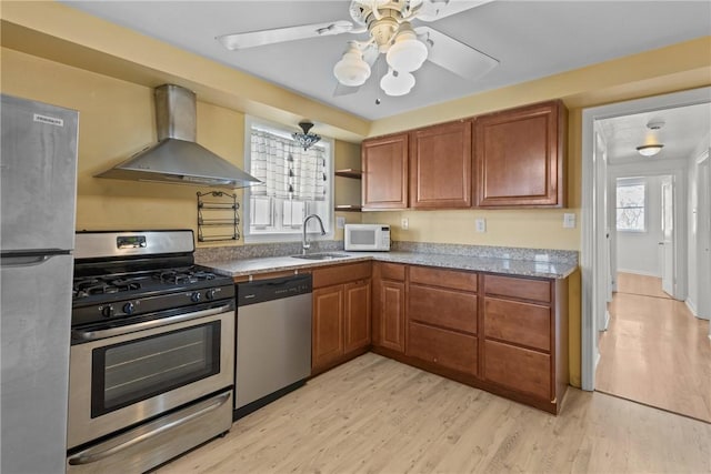 kitchen featuring brown cabinetry, appliances with stainless steel finishes, wall chimney range hood, and a sink