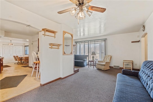 carpeted living area with visible vents, arched walkways, baseboards, and ceiling fan