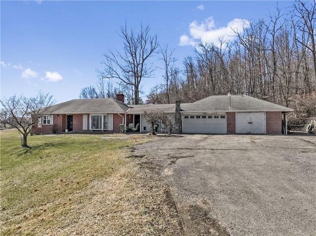 ranch-style home featuring brick siding, an attached garage, a front lawn, a chimney, and driveway