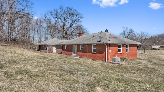 rear view of property with a lawn, brick siding, central AC, and a chimney