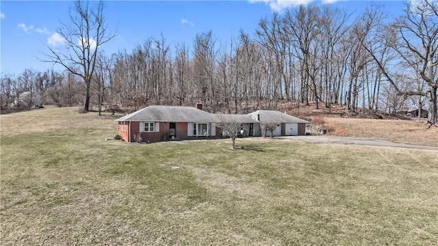 view of front of property with driveway, a front yard, an attached garage, brick siding, and a chimney